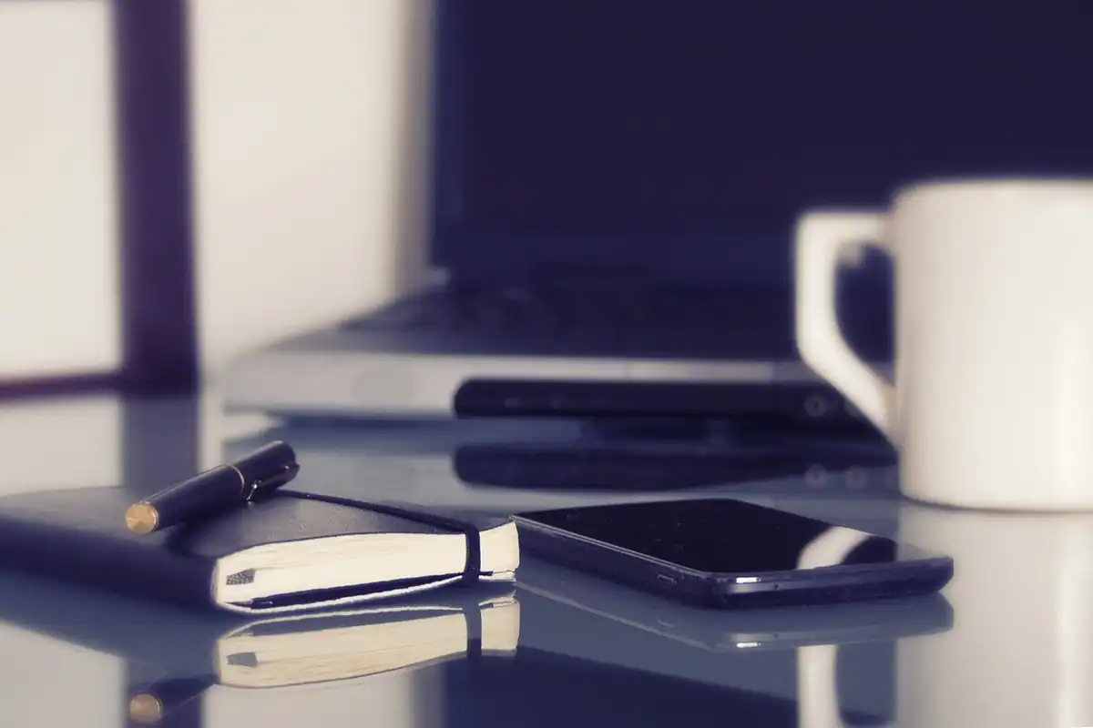 Telefon mobil, agendă și cană pe masă, unelte pentru notițe digitale și pe hârtie