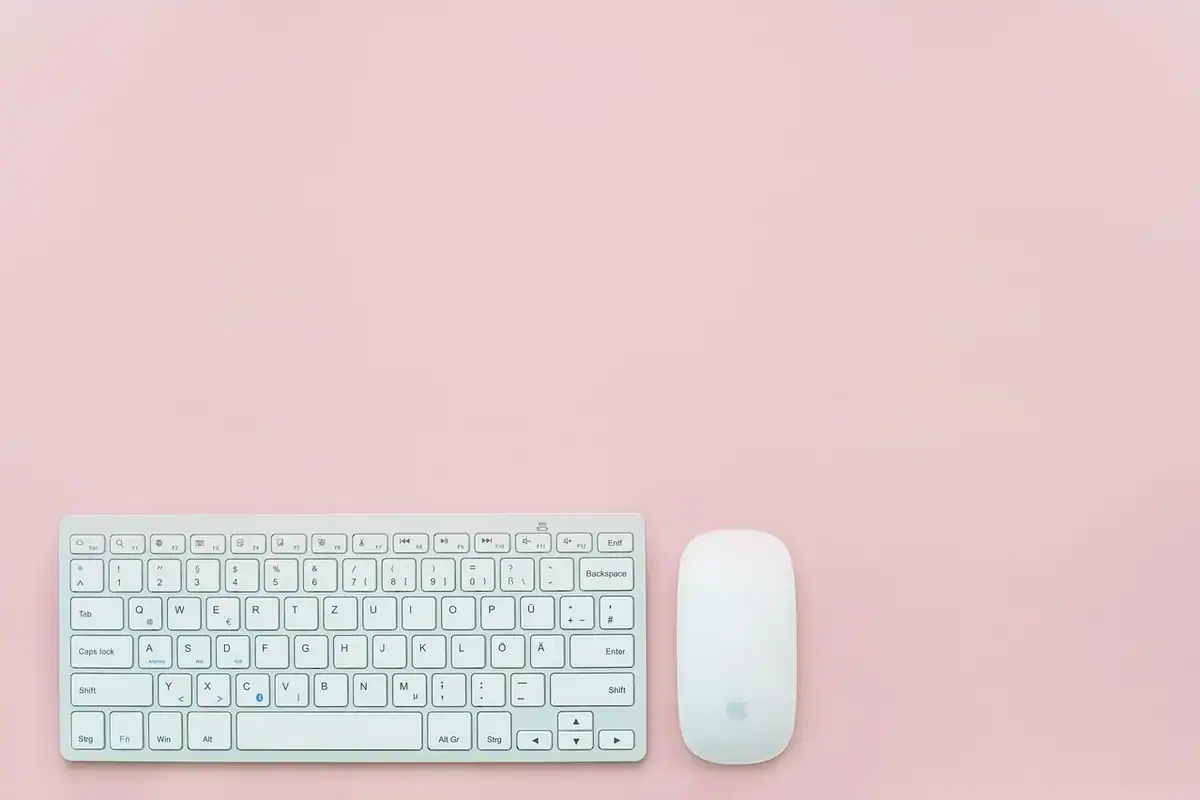 Tastatură mică albă și mouse pe un fundal roz, locul de unde începe diagnosticarea