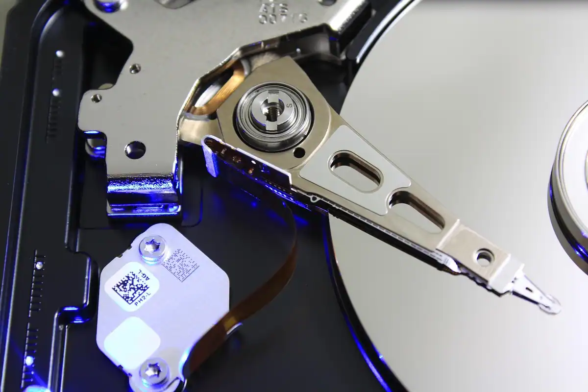 Platanul argintiu al unui hard disk și brațul de citire, fotografiate de aproape