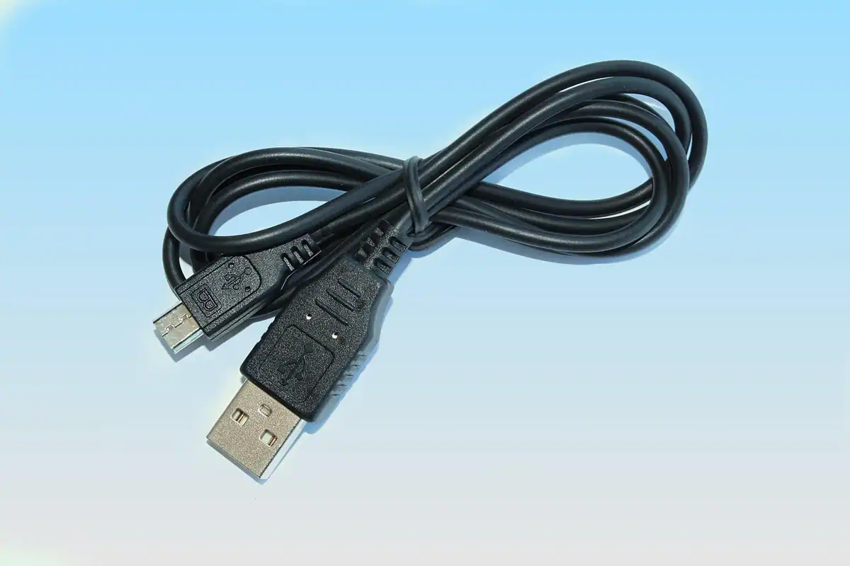 Cablu USB negru cu mufă micro, așezat în bucle pe fundal albastru deschis