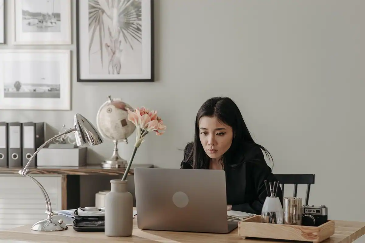 Femeie care lucrează la laptop la un birou de acasă