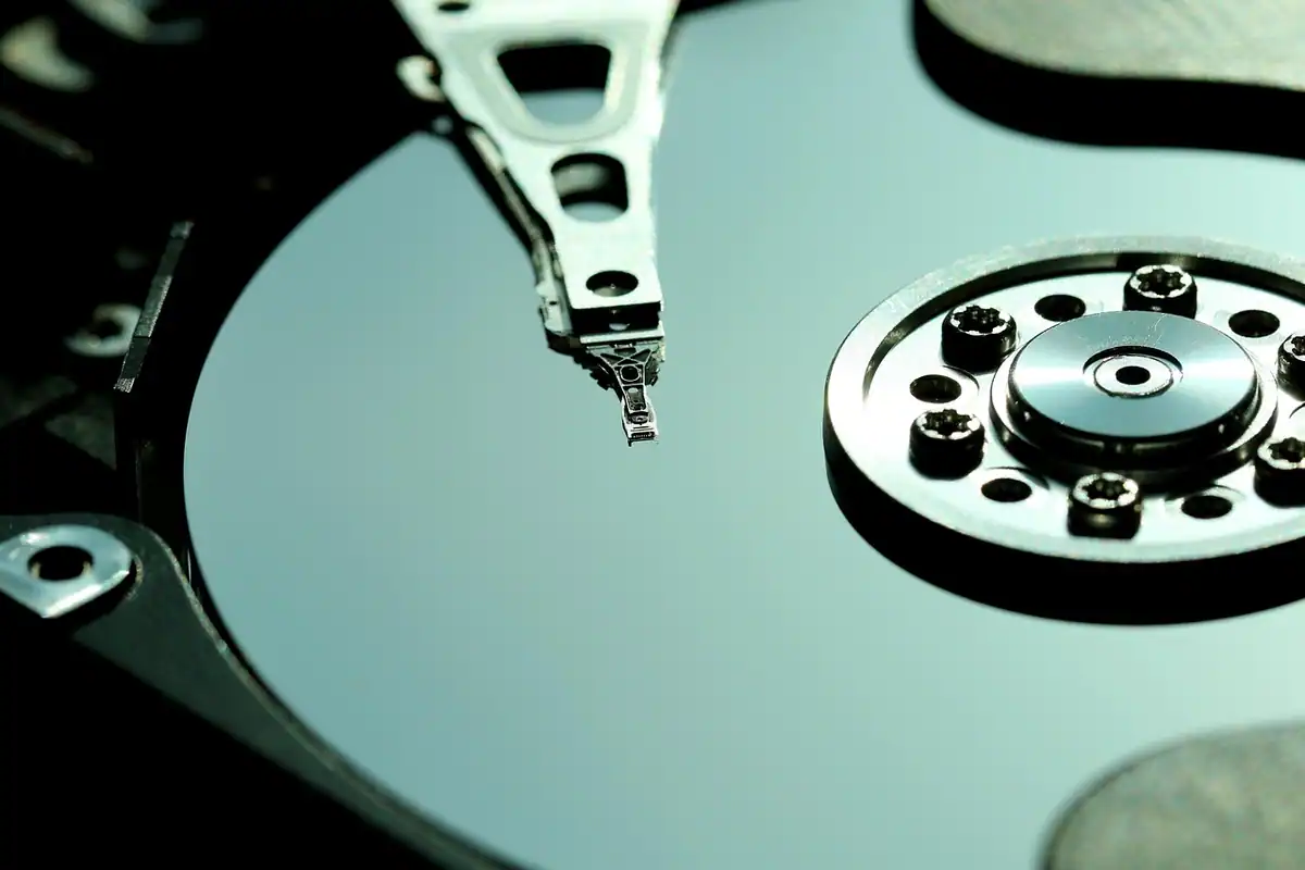 Hard disk deschis, cu platanul lucios și brațul de citire, vedere apropiată