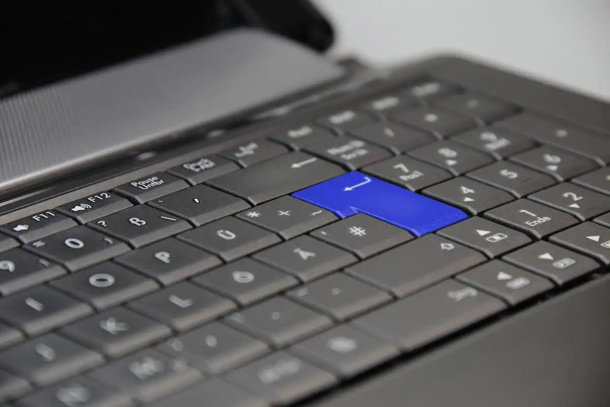 Tastatură de laptop gri, cu o singură tastă albastră evidențiată printre celelalte