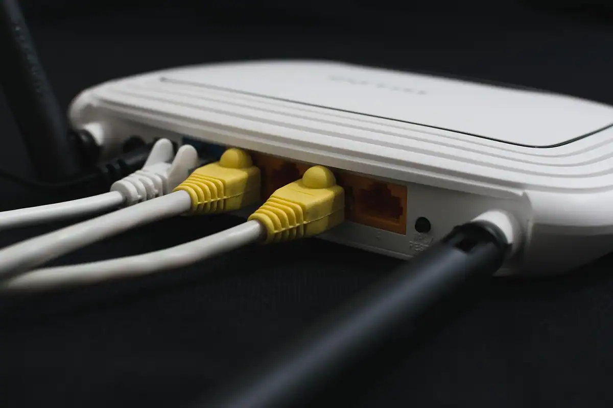 Spatele unui router alb, cu cabluri de rețea galbene și alb conectate
