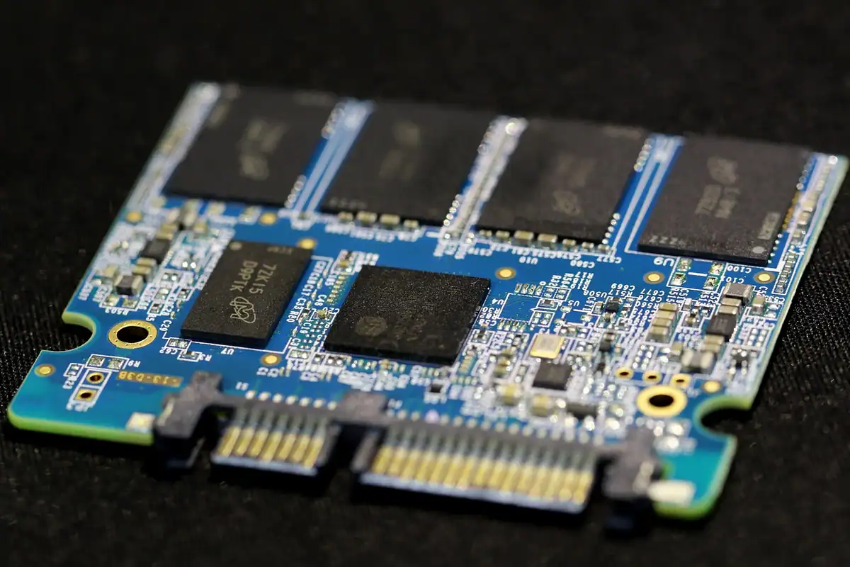 Unitate SSD cu plăcuța electronică albastră și cipuri de memorie, pe fundal negru