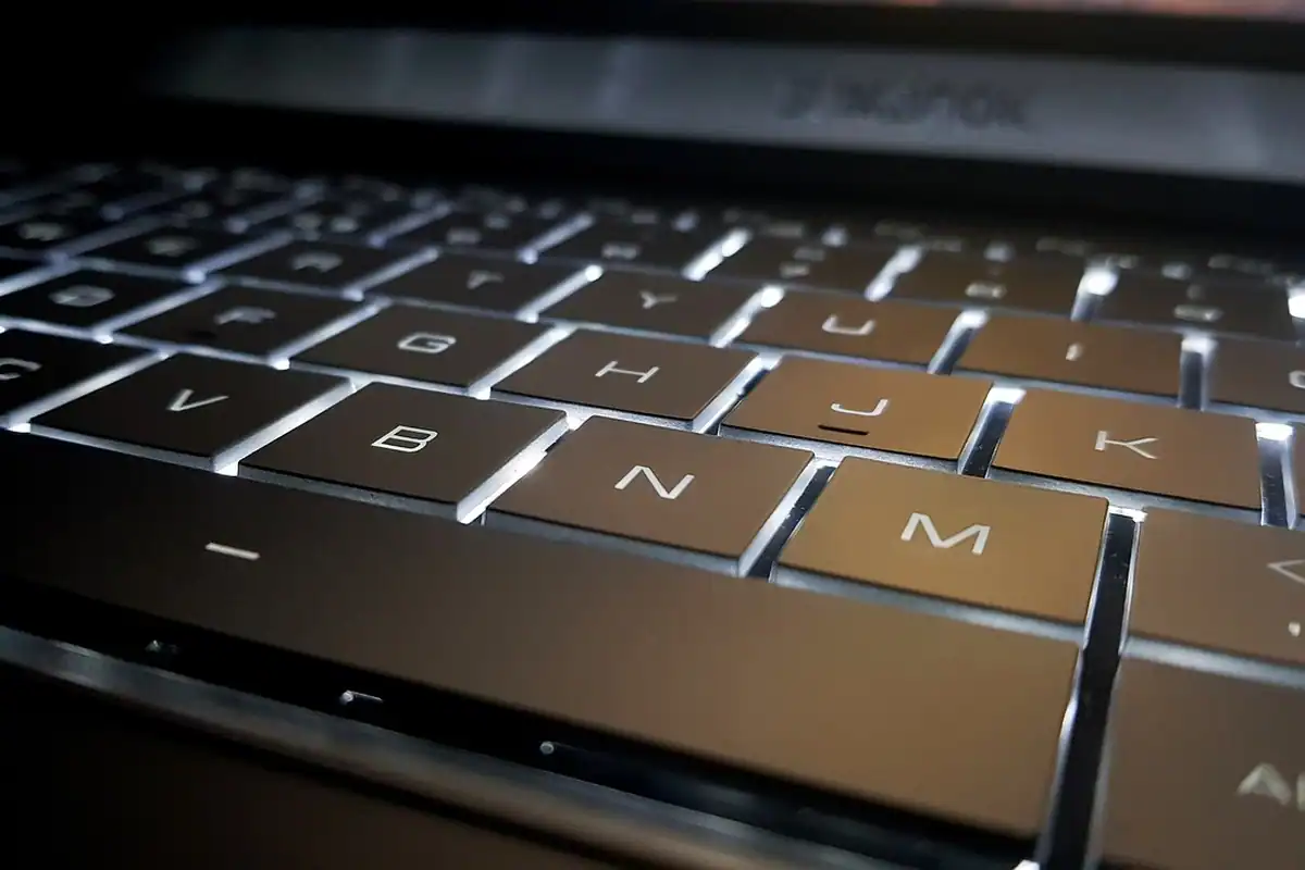 Tastatură de laptop subțire, cu taste luminate alb, văzută din unghi apropiat