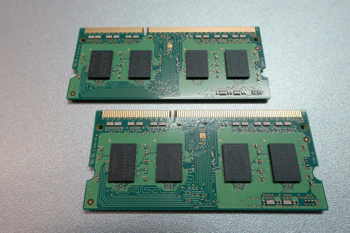 Două module de memorie RAM pentru laptop, așezate pe o suprafață gri